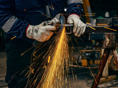 Close up of heavy industry worker's hands grinding in metallurgy factory.