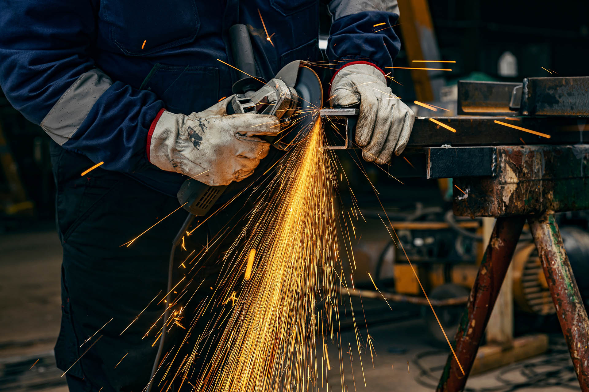Close up of heavy industry worker's hands grinding in metallurgy factory.